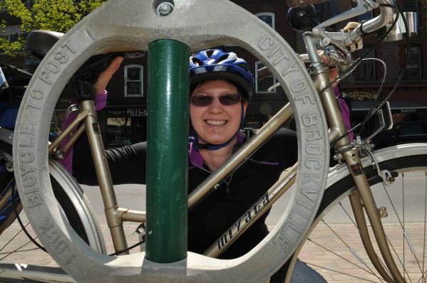 Kathleen Lowe, of the Brockville cycling advisory committee, places her bicycle by one of the bike parking rings placed on King Street to lure more cyclists downtown.